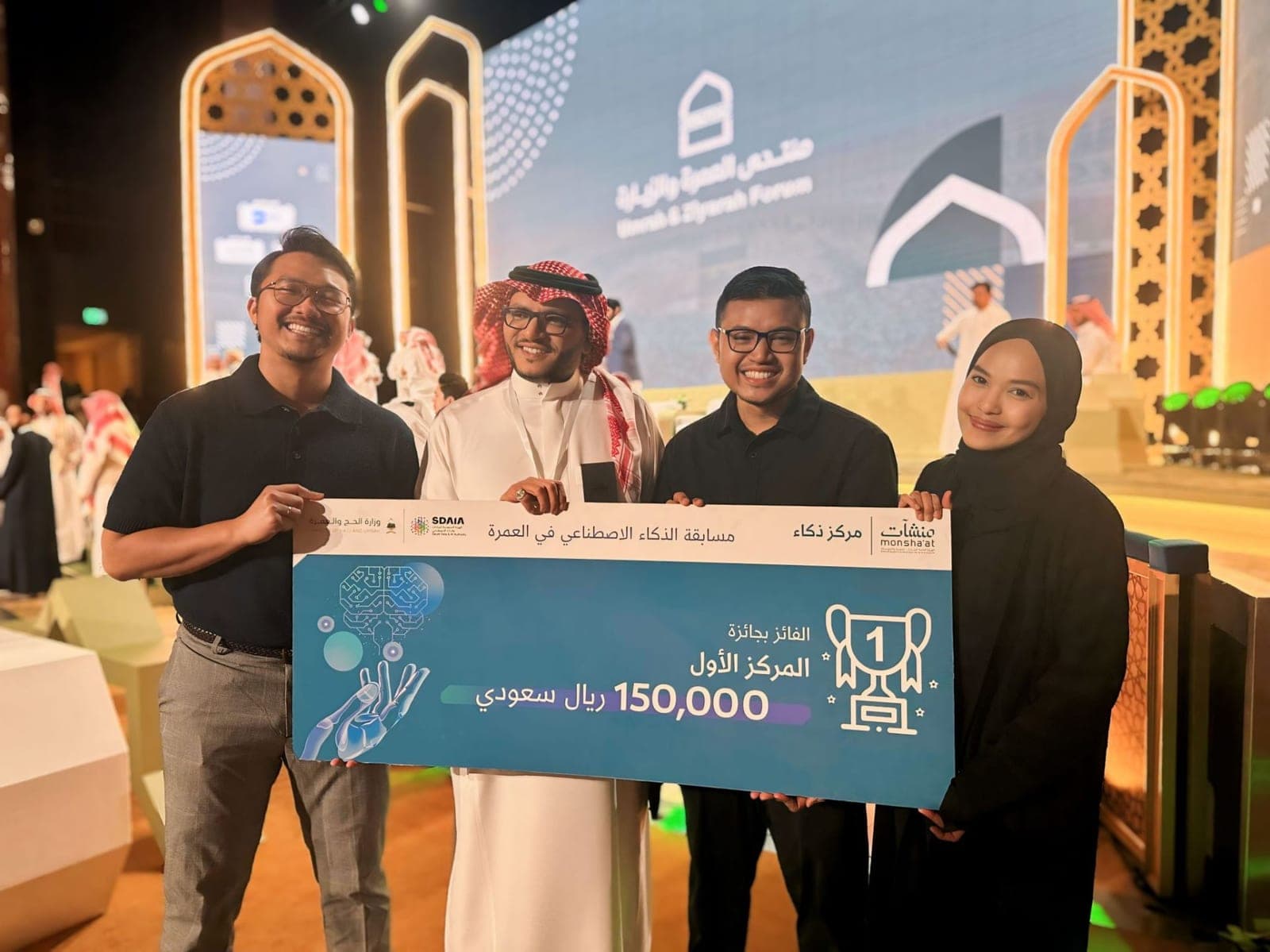Jihar with three others holding the first-place cheque for 150,000 Saudi riyals at the Umrah and Ziyarah Forum